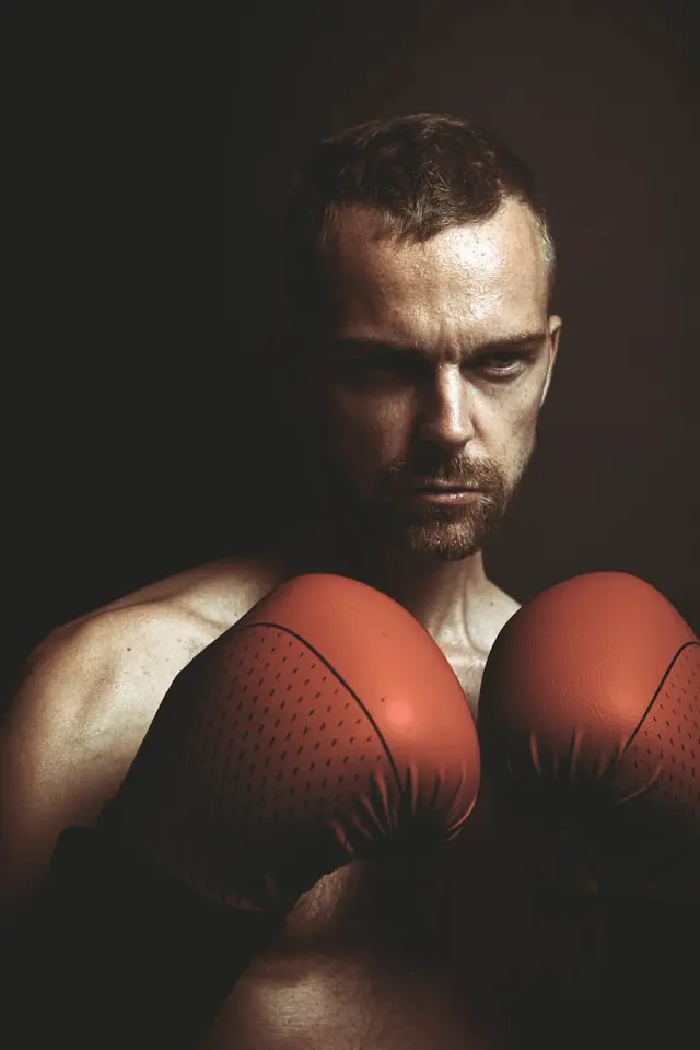 Retrato de Iván Roldán con guantes de boxeo rojos en escena oscura