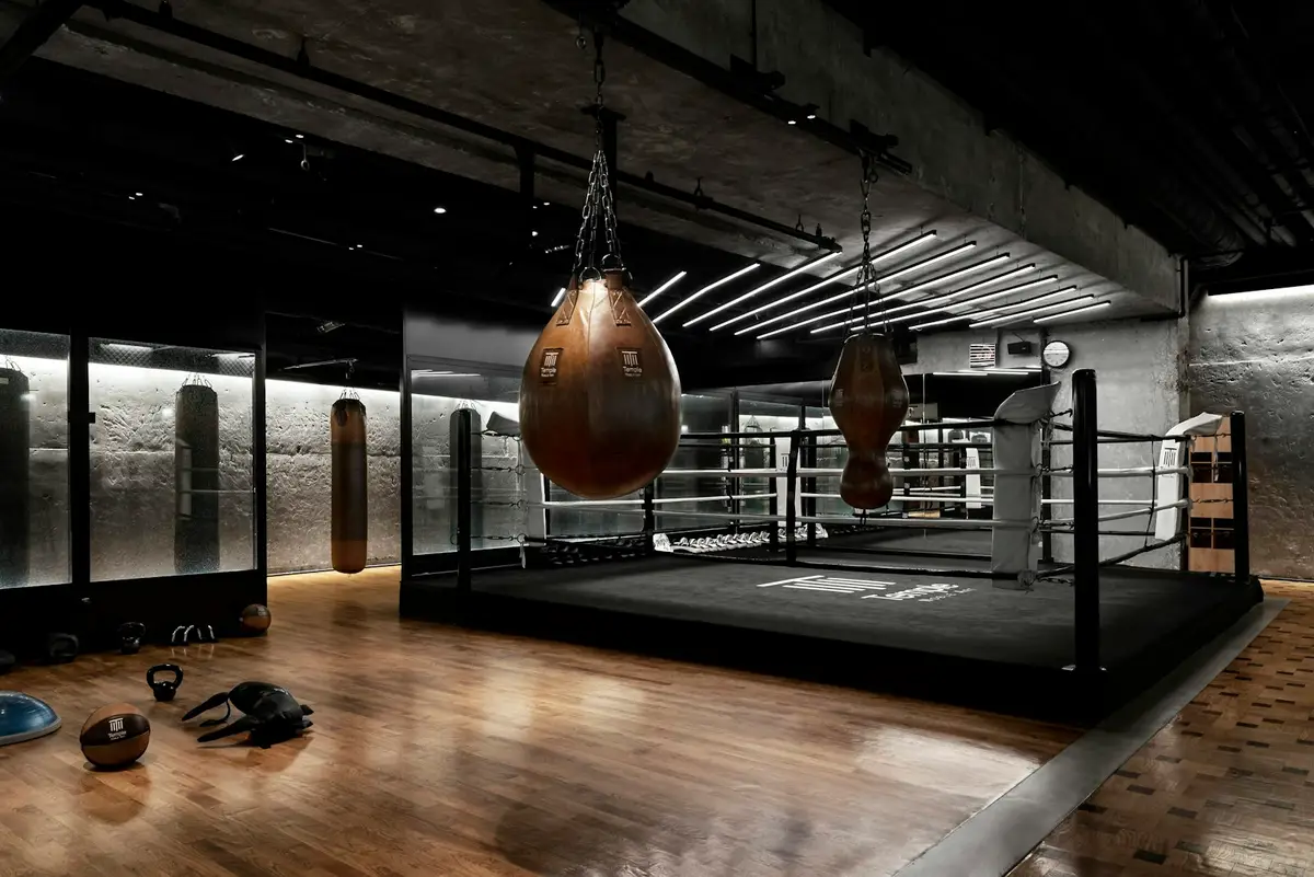 Ring de boxeo con sacos pesados colgando en el gimnasio del club