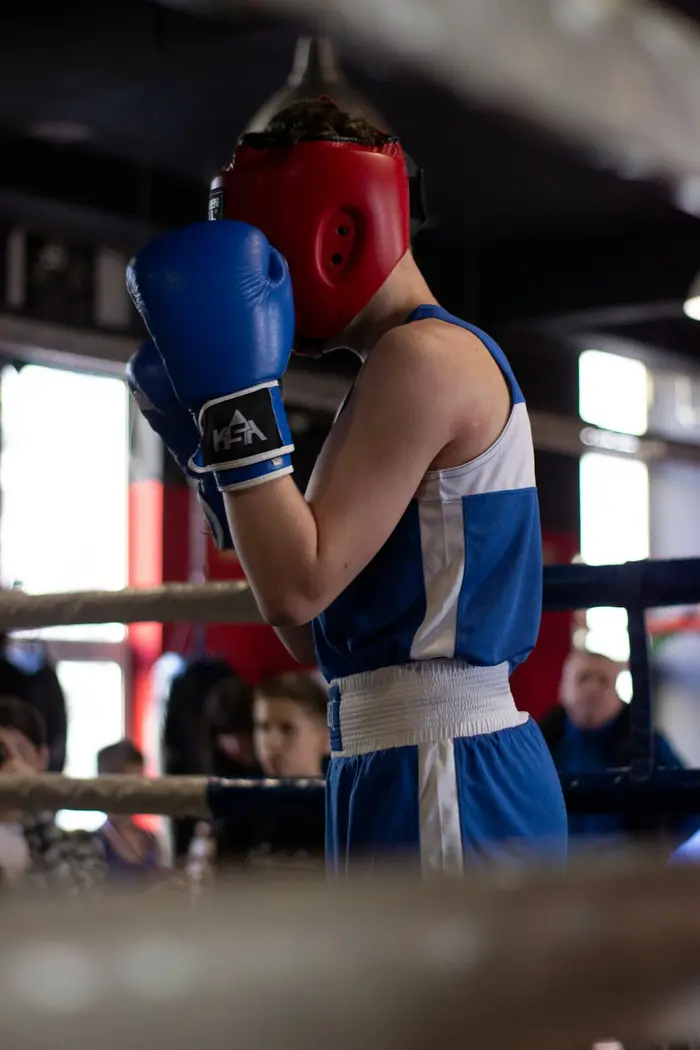 Niño con casco y guantes de boxeo azules en un ring