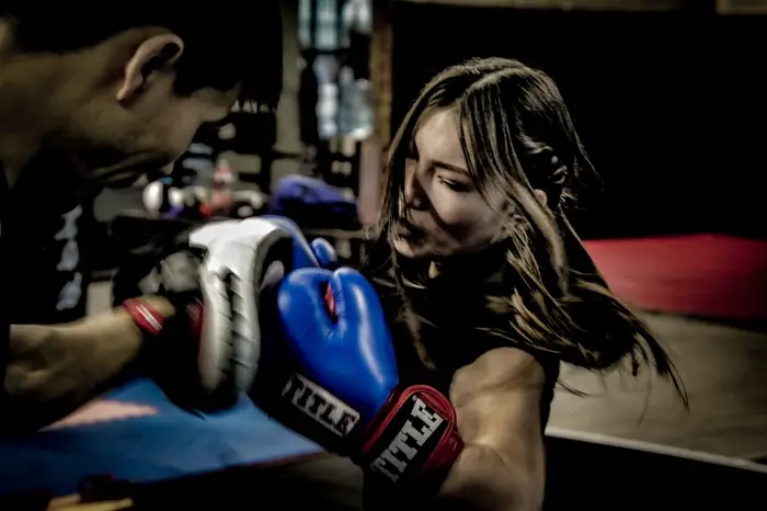 Entrenador y alumna trabajando de cerca con manoplas de boxeo