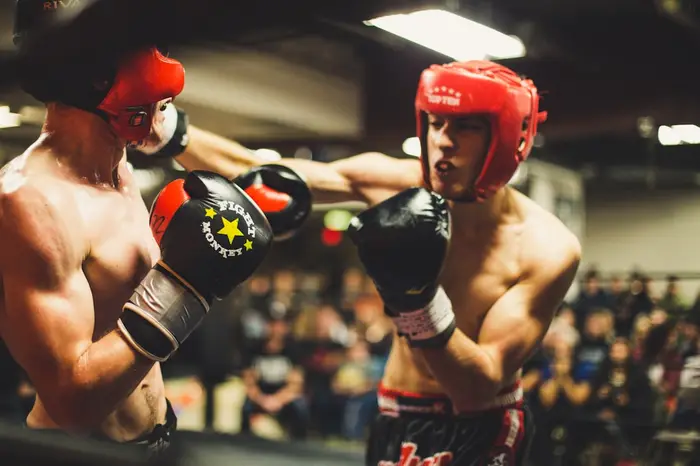 Dos boxeadores con casco intercambiando golpes en un combate de sparring
