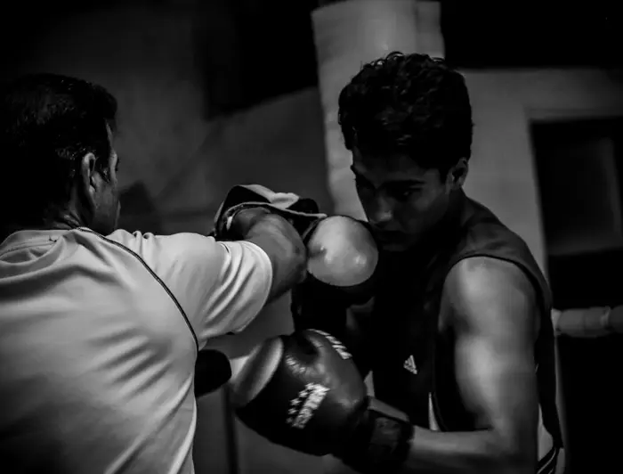 Entrenador sosteniendo una manopla mientras un boxeador practica el golpe